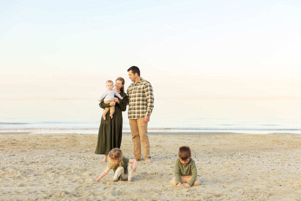 A virginia beach family plays together candidly during a golden sunset over the bay